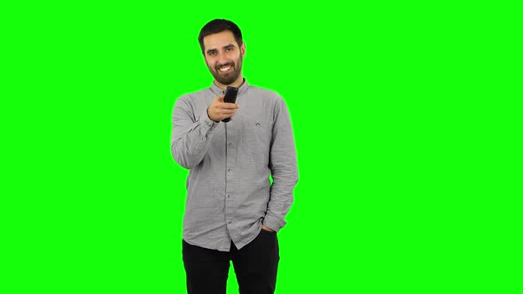 Brunette Guy with TV Remote in His Hand, Switching on TV. Green Screen