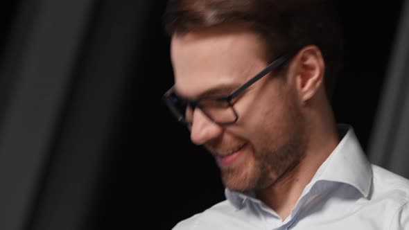 Smiling young man in eyeglasses communicating with colleagues