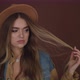 Attractive Woman in a Brown Hat and Denim Jacket Winds Her Hair on Her Fingers, Smiling - VideoHive Item for Sale