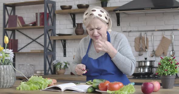 Mature Caucasian Woman Cutting Finger with Kitchen Knife As Cooking Salad at Home. Portrait of