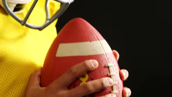 American football player holding ball against black background 4k