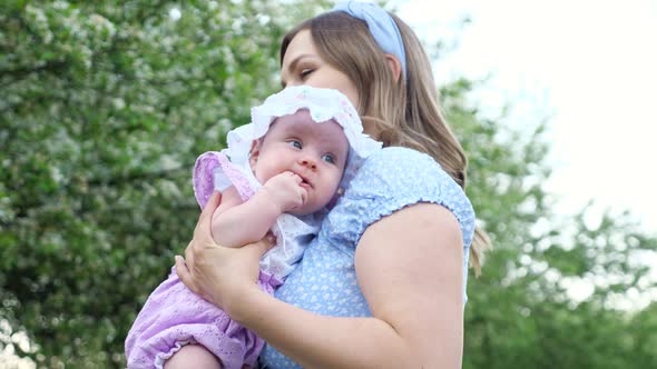 Careful Blonde Mother Holds Crying Female Kid and Lulls