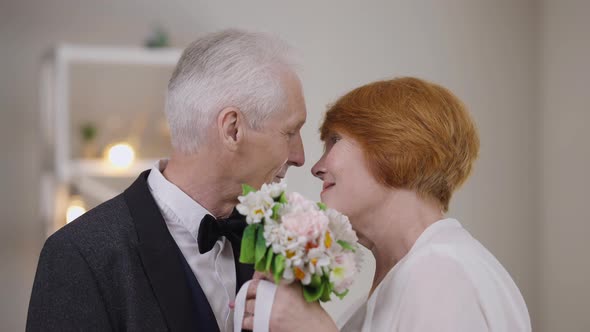 Closeup Loving Senior Couple Kissing Hiding with Bridal Bouquet