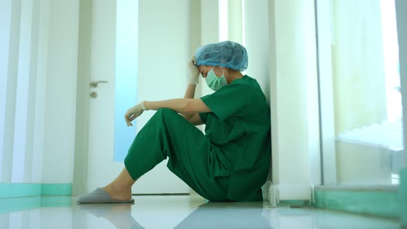 Side view of stressed and overworked female doctor medical worker surgeon sitting on the floor near