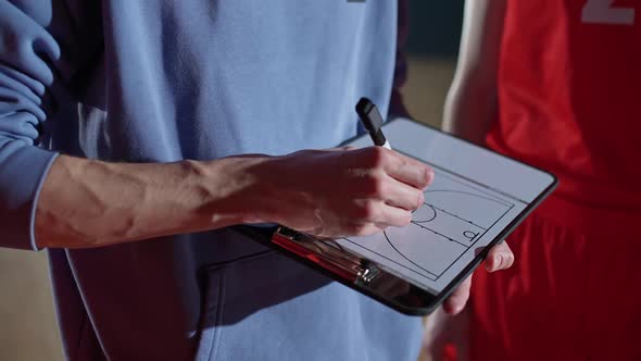 Basketball Championship Coach Instructs Players on the Tactics of the Game Using a Tablet and a