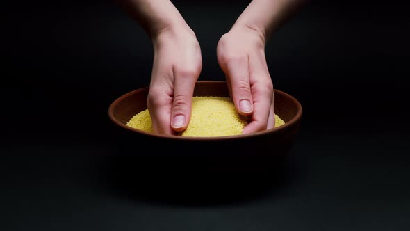 Taking Wheat Grains in Hands From Bowl on Black Background