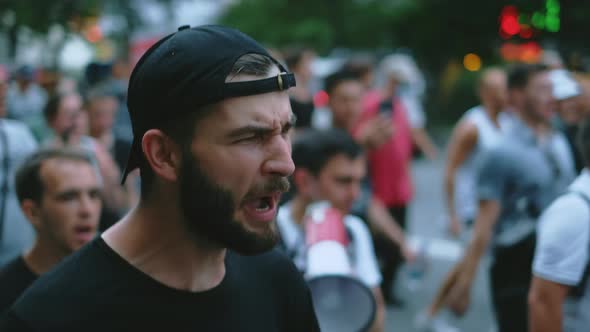 Demonstrator guy with beard walks and shouts in political opposition rally crowd