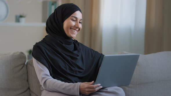 Happy Cheerful Islamic Young Girl Making Video Call Sit in Living Room Enjoy Pleasant Online