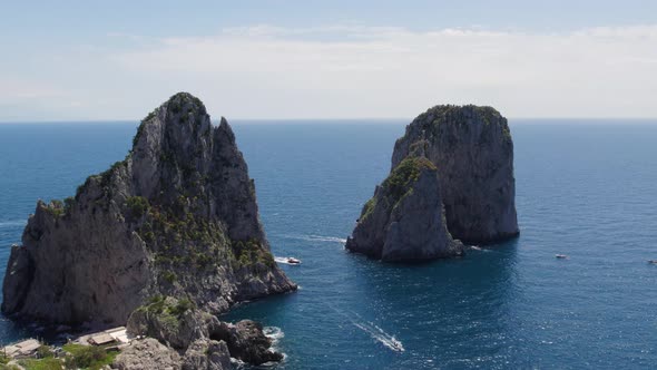 Craggy limestone masses of iconic Faraglioni sea stacks, Tyrrhenian Sea; drone