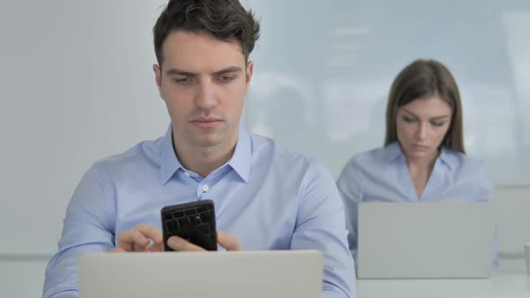 Young Businessman Using Smartphone at Work