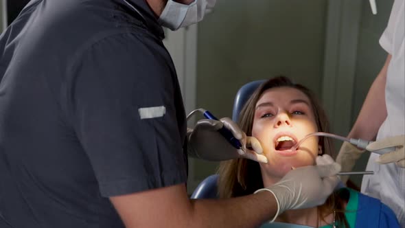 A Young Woman is at a Doctor's Appointment with a Dentist He Treats Caries