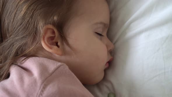 Authentic Cute Little Girl Sleeping Sweetly In Comfortable White and Grey Bed Close Up