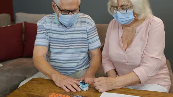 Senior Couple Grandfather and Grandmother Monitoring Oxygen Saturation with Digital Pulse Oximeter