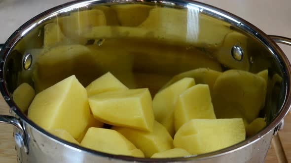 Chef Places Large Pieces of Raw Potatoes in Saucepan and Pour with Clear Cold Water