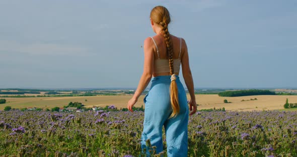 Young Woman Walks in Purple Flowers Field