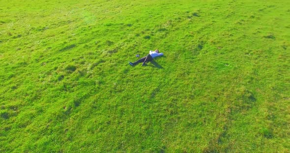 Low Orbital Flight Around Man on Green Grass with Notebook Pad at Yellow Rural Field