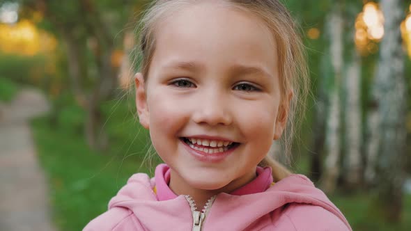 Portrait of Beautiful Little Girl Looking at Camera and Smiling in Summer Park