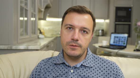 Young Adult Man Sitting on Sofa at Home and Looking at Camera Make Live Video Chat Conference Call