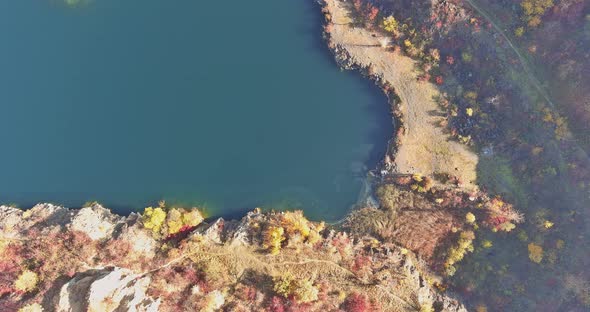 An Quarry Pond Formed During Mining Stone with Overgrown with Green Plants with Clear Turquoise