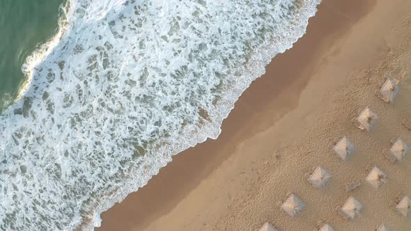 Sandy beach with straw sunshades and sunbeds