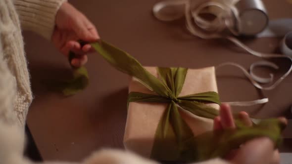 Closeup Top View of Unrecognizable Young Woman Tying Ribbon on Wrapped Christmas Gift Box with