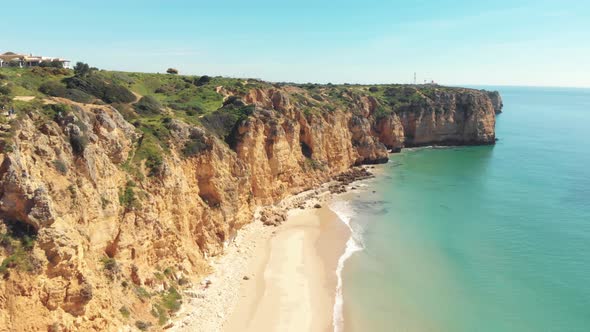 Canavial Beach framed by scenic cliffs in Lagos, Algarve, Portugal - Aerial Fly-over Tracking shot