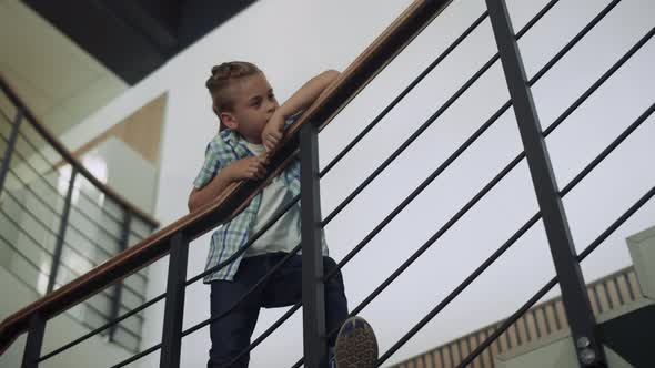 Schoolboy Leaning Stairs Railing Looking Corridor