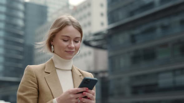 Positive Woman in Business Clothes Using Smartphone Outdoors