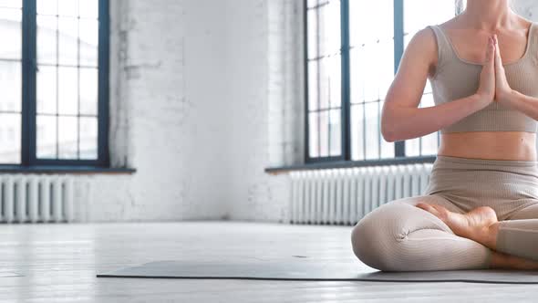 Slim woman in comfortable tracksuit meditates in yoga full lotus position