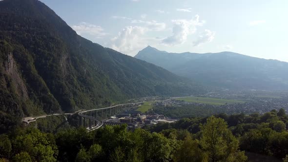 Aerial approach to an industrial area and huge bridge in the mountains. Polluted valley in the frenc