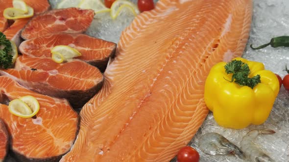 Composition of Trout and Salmon Steaks Lies on Ice in Showcase of Supermarket