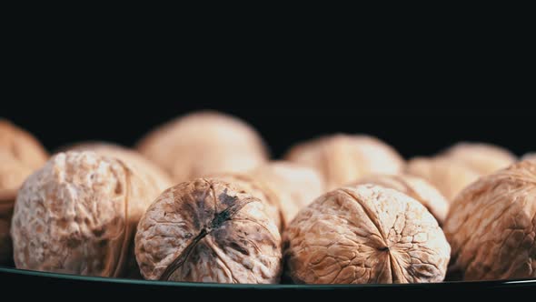 Lot of Walnuts in the Shell are Spinning on a Black Background