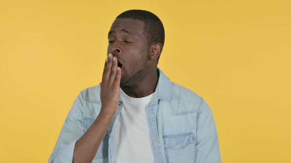 Sleepy Young African Man Yawning, Yellow Background 