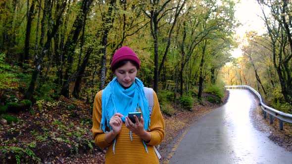 Woman with Backpack Using Smartphone Hiking In The Forest