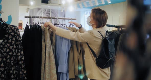 Happy Female Shopper Choosing New Dress at the Clothes Store After Quarantine Coronavirus