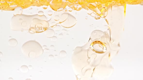 Slow Motion of Moving Yellow Golden Oil Air Bubbles in Water Rising Up on Light White Background