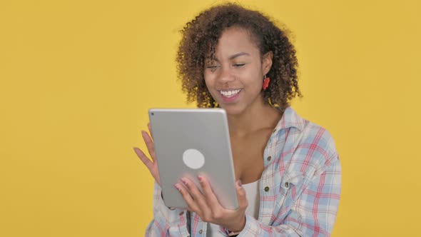 Video Call on Tablet By Young African Woman on Yellow Background