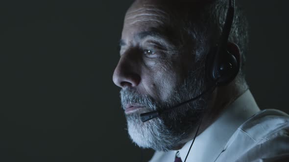 Mature Man in Headset Working in Dark Office