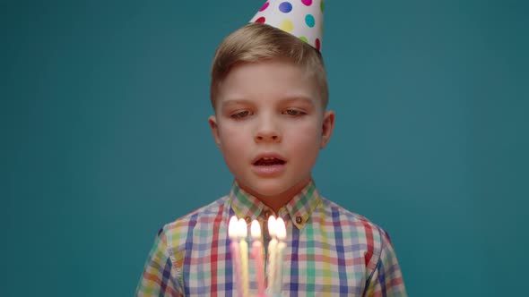 Little Birthday Boy Wearing Party Hat Blowing Birthday Candles and Making a Wish