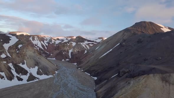 Aerial Flight over Snowy Volcanic Mountains and River Delta in Evening Iceland