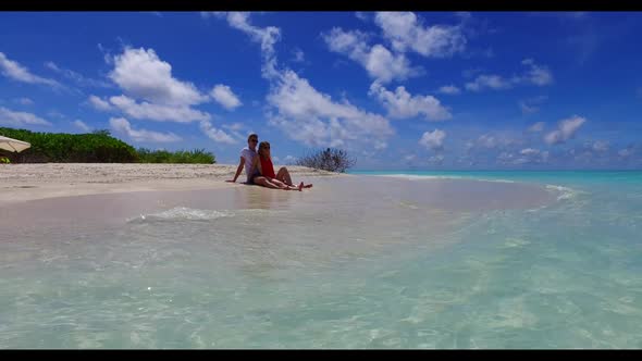 Young couple sunbathe on marine coast beach lifestyle by turquoise ocean with white sand background 