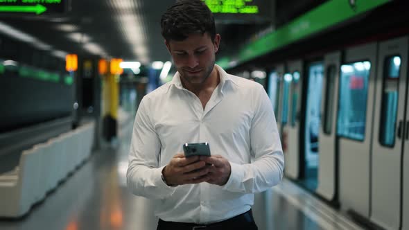 Positive Male Manager with Cellphone Walking on Platform
