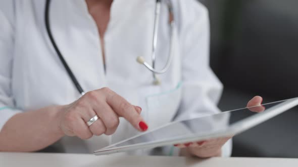 Close up Middle Aged Older Female Doctor in White Uniform Holding Digital Computer Tablet in Hands