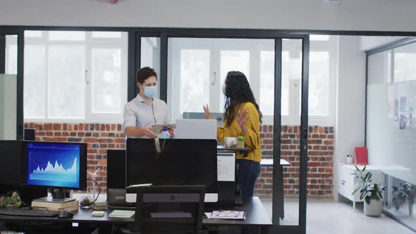 Man and woman wearing face mask working together in office