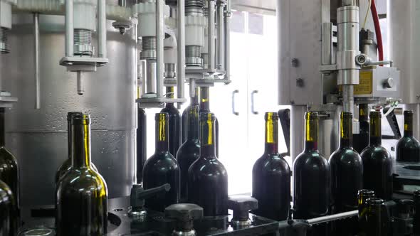 Machinery in a wine factory as the full bottles of red wine are being corked