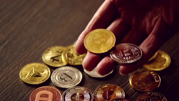 Man hand holding crypto coins and golden bitcoin on a table