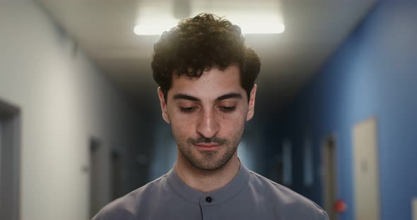 Young Doctor Smiles Looking at the Camera Standing in Corridor of the Hospital