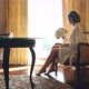 Young Bride Is Sitting By the Window in a Luxury Hotel with a Bouquet of Flowers - VideoHive Item for Sale