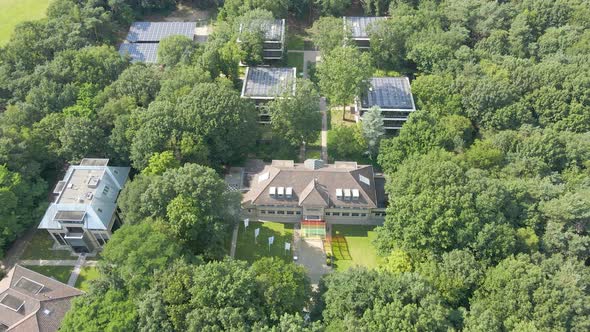 Aerial of convention center with small office buildings with solar panels on rooftop in forest