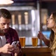 Young Couple In A Bar Arguing Over The Time He Spend On Social Media With His Smartphone - VideoHive Item for Sale